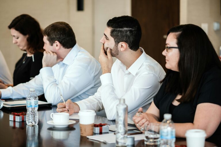 A diverse group of professionals engaged in a business meeting, collaborating and taking notes.